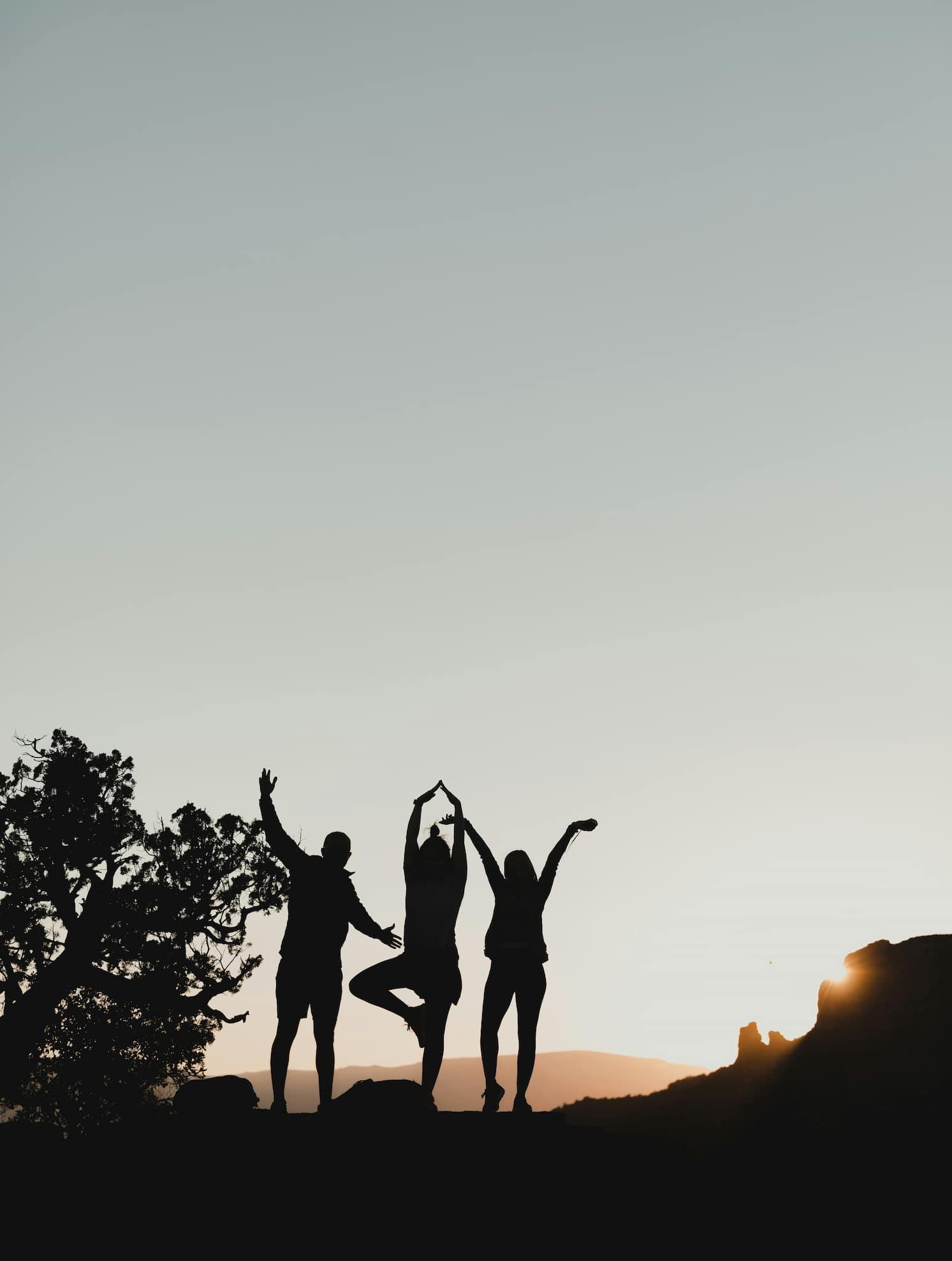 A group of people standing on a hill, sunset